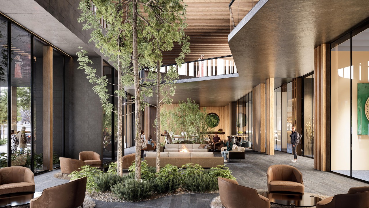 A nature-inspired hotel lobby at The Slope in Heber, featuring interior trees, lounge seating, and large floor-to-ceiling windows.