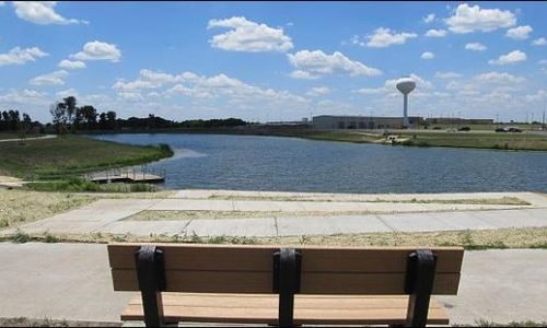 Rose Hill, KS A bench overlooks a large pond, the water tower can be seen in the background