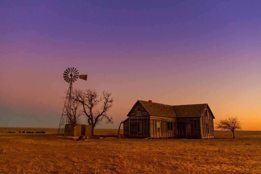 Home in undesirable location An old home sits next to a windmill in the middle of nowhere