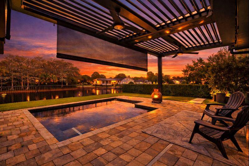Open-air heated pool and turf putting green at sunset at a Lake Worth lakefront home in Woods Walk 2