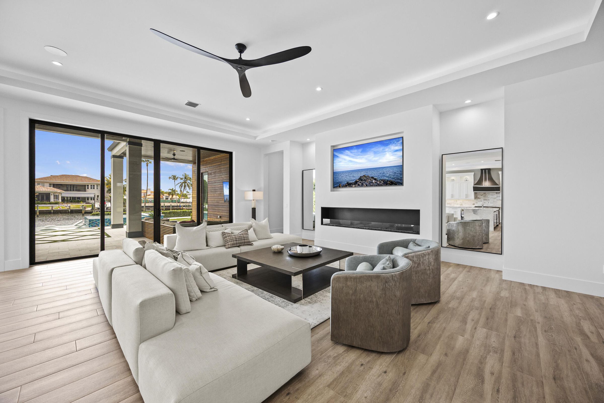 Sala moderna con puertas corredizas hacia la piscina waterfront en North Palm Beach