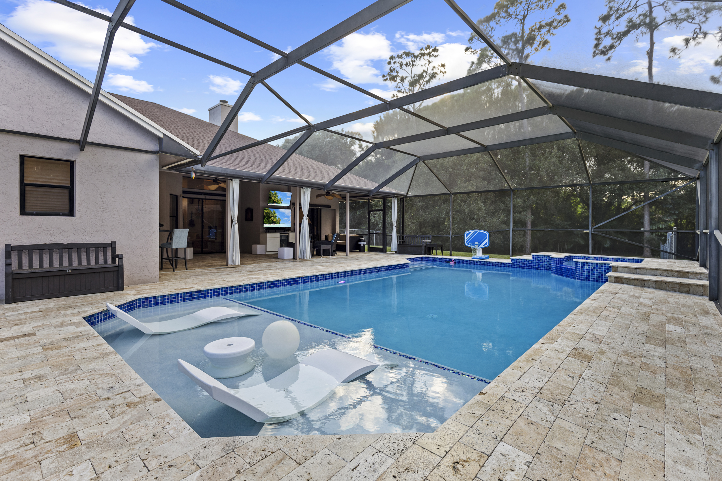 Screen enclosed pool with travertine deck at Loxahatchee Acreage home