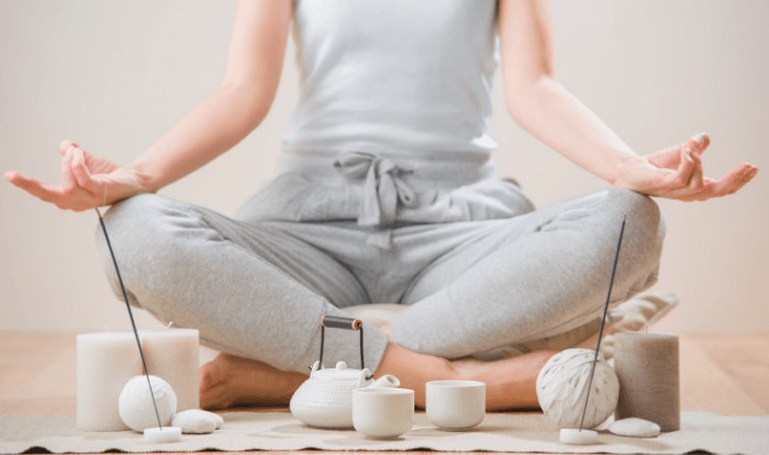woman meditating among candles and incense